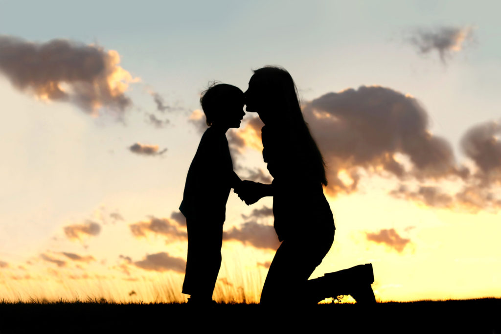 Mother Lovingly Kissing Little Child at Sunset